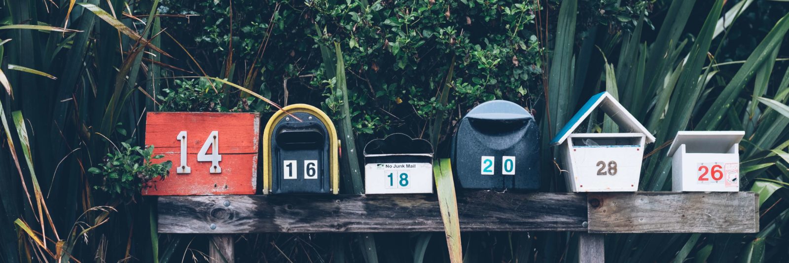 variety of mailboxes on wooden rail with house numbers